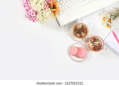 Modern Woman's Desktop, Home Office. Computer, A Cup Of Herbal Chamomile Tea And Spring Flowers On A Pastel Table. Minimal Business Concept, Hello Summer, Home Comfort, Top View, Flat Lay