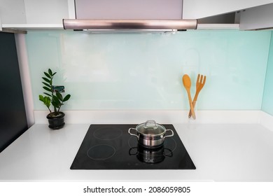Modern Wood kitchen with granite white countertops and have modern black induction hob, Stainless steel slim line cooker hood 60cm, Open wall cabinet. ฺ Blue glass wall.