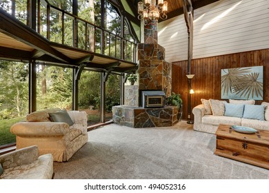 Modern Wooden Cottage House Interior With Living Room Close Up. Gorgeous Fireplace With Natural Stone Tile Trim And Large Glass Wall. Northwest, USA