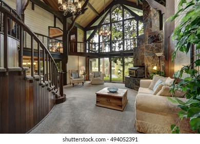 Modern wooden cottage house interior with living room close up. Gorgeous fireplace with natural stone tile trim and large glass wall. Northwest, USA