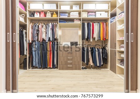 Modern wooden wardrobe with clothes hanging on rail in walk in closet design interior