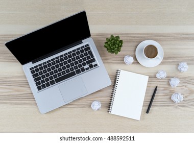 Modern working place on wooden table. Working place surrounded with notepad, coffee, pen, rubber, plant, iphon and macboo. Blank copy space view from above or top view. Dead ideas paper.