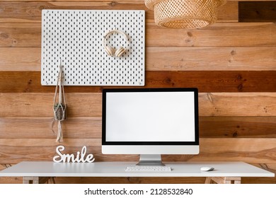 Modern Workplace With Computer And Peg Board Hanging On Wooden Wall