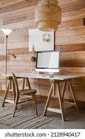 Modern Workplace With Computer And Peg Board Hanging On Wooden Wall