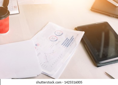 Modern workplace with digital tablet computer and mobile phone, cup of tea, pen and papers with numbers and diagrams. - Shutterstock ID 1425516005