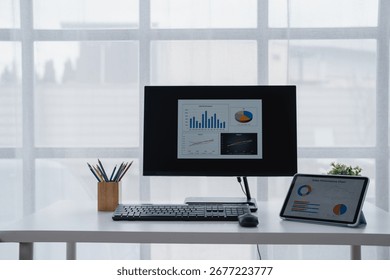 Modern workplace featuring a computer displaying various charts and graphs, indicating data analysis and business performance review in a bright office environment