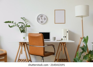 Modern Workplace With Laptop Near Light Wall With Clock