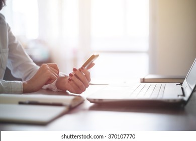 Modern workplace woman using mobile phone in office.