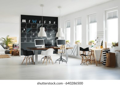 Modern Workspace With Blackboard Calendar, Desk, Chairs And Computers