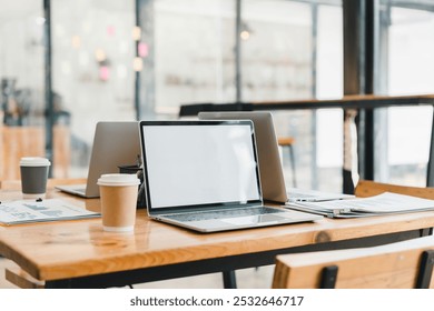 modern workspace featuring laptops, coffee cups, and documents on wooden table. clean and organized setup promotes productivity and creativity in contemporary office setting.
