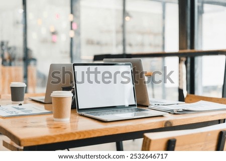 modern workspace featuring laptops, coffee cups, and documents on wooden table. clean and organized setup promotes productivity and creativity in contemporary office setting.