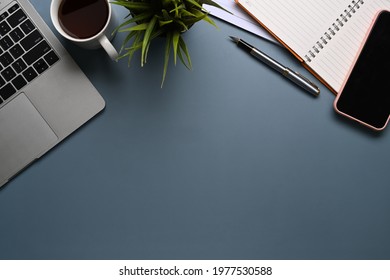 Modern workspace with laptop computer, coffee cup, notebook and smart phone on dark blue leather. Stock Photo