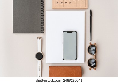 Modern workspace with smartphone, wristwatch, magazine, sunglasses, notebook, copy space on beige background. Top view. Flat lay style. - Powered by Shutterstock