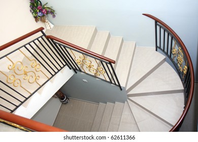 Modern Wrought Iron Spiral Staircase Lined With Wooden Handrail.