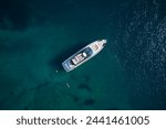 Modern yacht on clear blue water from above. People swim around the yacht, top view. Expensive yacht on blue water aerial view.