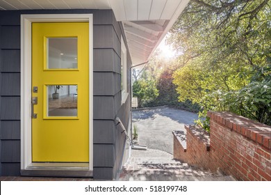 Modern yellow front door with stainless steel handle and glass.