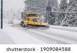 Modern yellow snowplow driving along road in winter removing snow