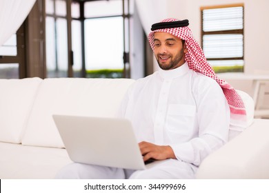 Modern Young Arabian Man Using Laptop Computer At Home