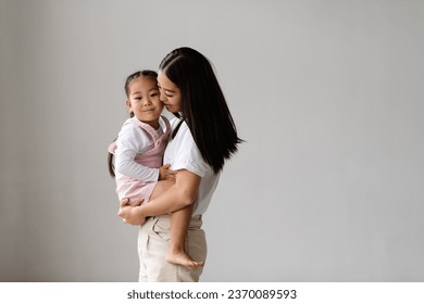 Modern young asian mother holding smiling baby daughter isolated on grey with copy space - Shutterstock ID 2370089593