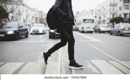 Modern young bearded man in black style clothes is walking at street.