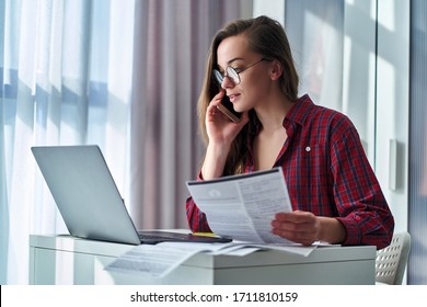 Modern young casual attractive freelancer woman in glasses holds cv resume and talking on the phone during job search online - Shutterstock ID 1711810159