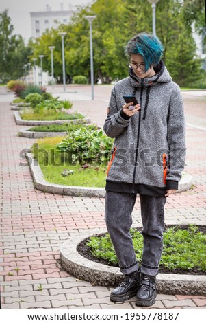 Modern young girl reads messages on the smartphone screen on the city street. Online communication. Life style.