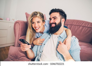 Modern young happy couple enjoying at home and watching TV