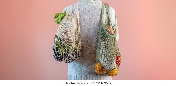 A Modern Young Man Is Carrying A String Bags With Purchases. Concept Of Eco-friendly Behavior, The Use Of Reusable Bags And Concern For The Environment