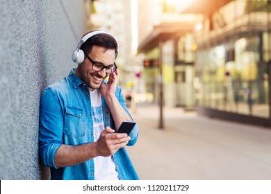 Modern young smiling man enjoying music outdoor