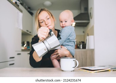 Modern Young Tired Mom And Little Child After Sleepless Night. Exhausted Woman With Baby Is Sitting With Coffee In Kitchen. Life Of Working Mother With Baby. Postpartum Depression On Maternity Leave.