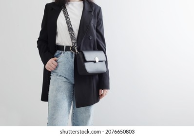 Modern Young Woman In Black Blazer And Blue Jeans On White Background