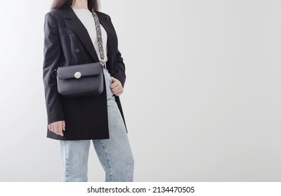 Modern Young Woman In Black Blazer And Blue Jeans On White Background