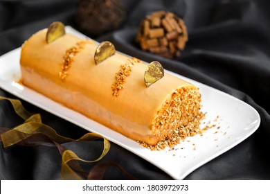 modern yule log with caramel topping , hazelnut chip and meringue on black background - Shutterstock ID 1803972973