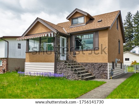 Modest family house with green lawn in front. Old residential house