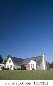 Modest Suburban Home With Tall Blue Sky And Lawn