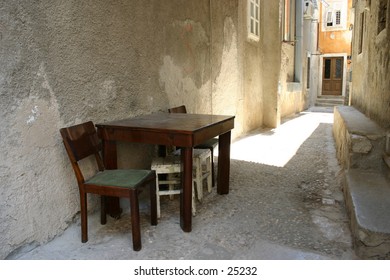 A modest wooden table and a chair against a wall. At Cres, Island Cres, Croatia