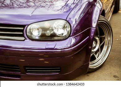 Modified headlights of tuned purple candy colored lowrider. Stance custom car with a forged polished wheels stays on a street
