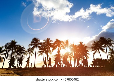 Modified Silhouettes Of People Walking At Sunset On Crowded Kalakawa Ave - Front Walk Street Of Waikiki Beach In Honolulu Hawaii - Enhanced Sunlight Warm Filter With Lens Flare As Part Of Composition