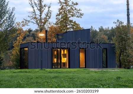 Modular apartment of frame type , sheathed in wood against the background of an autumn forest . Mobile eco-friendly space for living and tourism .