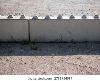 Modular concrete retaining wall system on gravel surface. Precast construction blocks used for slope support, landscaping, infrastructure projects and site development.