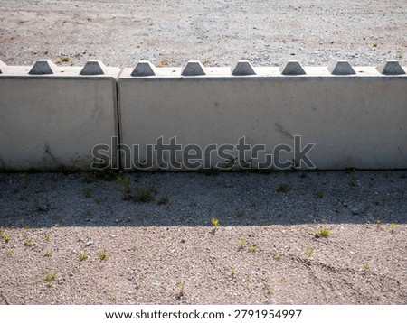 Modular concrete retaining wall system on gravel surface. Precast construction blocks used for slope support, landscaping, infrastructure projects and site development.