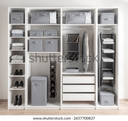 Modular open closet system featuring grey fabric bins, shoe organizers, hanging shelves, and folded textiles, designed to highlight minimalist organization, cleanliness, and modern storage efficiency.