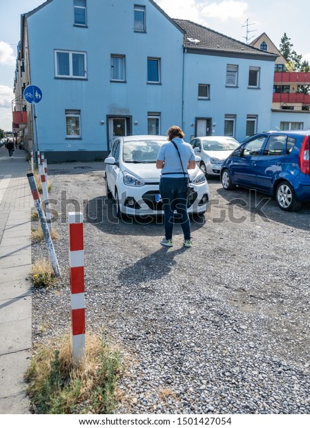 MOERS / GERMANY - AUGUST 16 2019\
: German parking inspector taking notes to issue a parking\
fine.