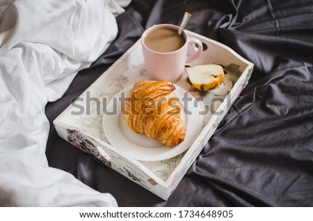 Mofning in the bed. Beakfast with croissant and coffee with milk and fruit.