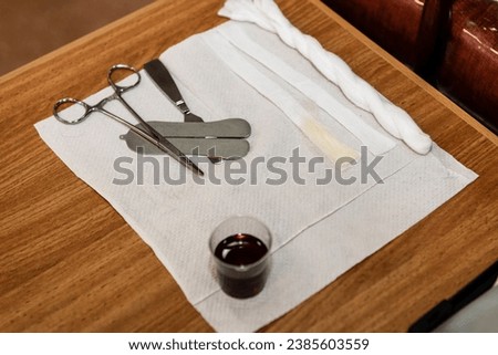 A mohel or ritual circumcisor prepars the instruments and ritual items, including wine, alcohol swabs and a knife, before performing a brit mila or circumcision on an young Jewish male baby.