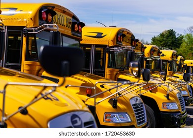 Mohnton, PA / USA - May 2, 2020: A line of parked school buses in a parking lot in Berks County, Pennsylvania.
