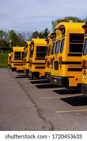 Mohnton, PA / USA - May 2, 2020: A rear view of a line of parked school buses in a lot in Berks County, Pennsylvania.