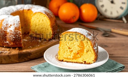 Moist orange pound cake slice on a plate with powdered sugar topped bundt cake ready to enjoy