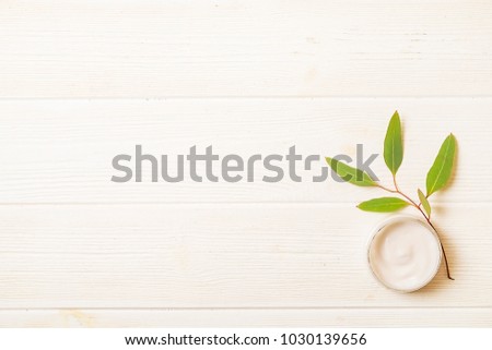 Moisturizer face body skin care wrinkle cream & eucalyptus leaves on white wood textured table background. Retinol moisturizing anti aging antioxidant skincare product for women. Copy space, close up.