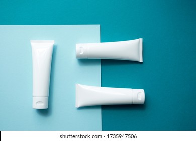 Moisturizer Hand Cream White Plastic Tubes Mockup On Blue Trendy Paper Background, Top View. Blank Skin Care Beauty Product Packaging